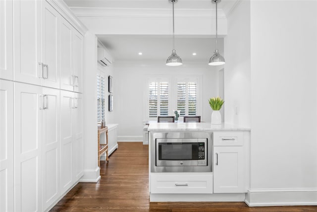 kitchen featuring white cabinets, stainless steel microwave, dark wood-style flooring, crown molding, and an AC wall unit