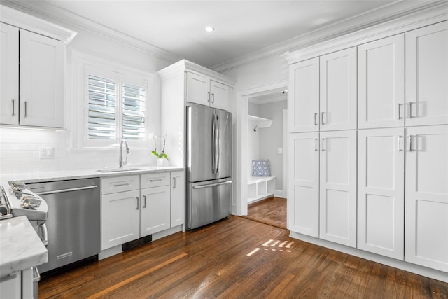 kitchen with dark wood-style floors, stainless steel appliances, crown molding, white cabinetry, and a sink