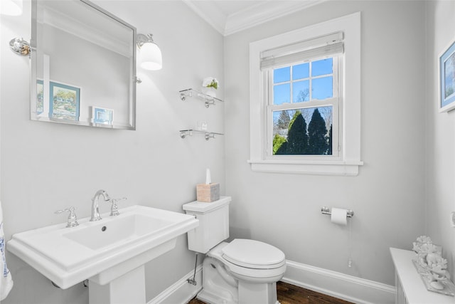 bathroom featuring baseboards, toilet, ornamental molding, wood finished floors, and a sink