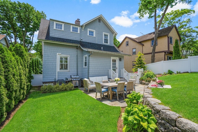 rear view of house featuring a shingled roof, a fenced backyard, a patio, and a chimney