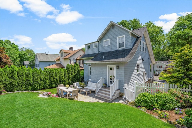 back of property with a patio area, roof with shingles, fence, and a yard