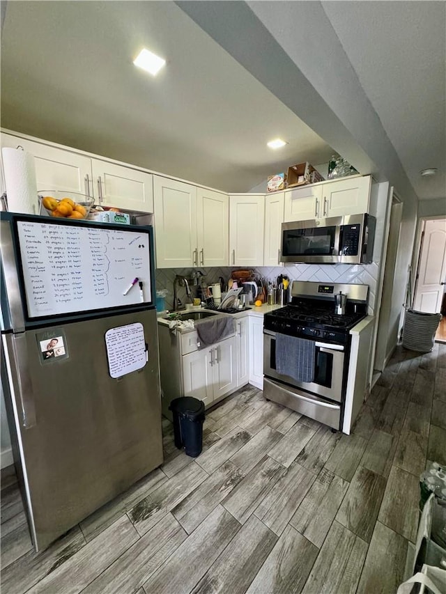 kitchen featuring decorative backsplash, white cabinetry, appliances with stainless steel finishes, and light hardwood / wood-style flooring