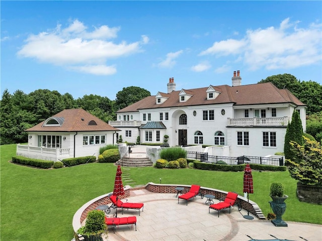 back of house with a lawn, a balcony, a patio, and a fire pit