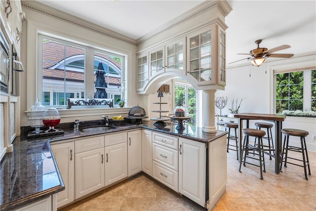 kitchen with plenty of natural light, kitchen peninsula, and ornamental molding