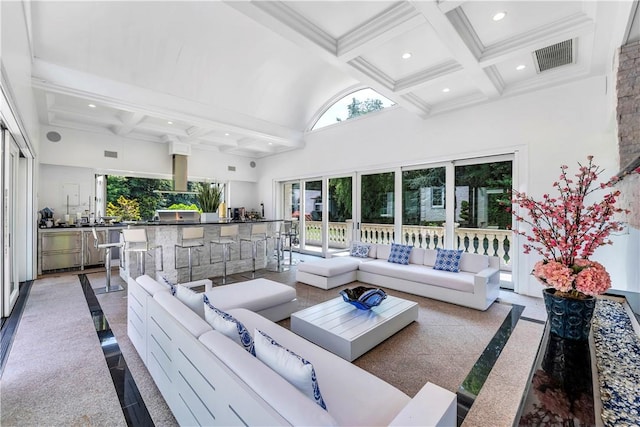 living room with a high ceiling, coffered ceiling, a healthy amount of sunlight, and beam ceiling