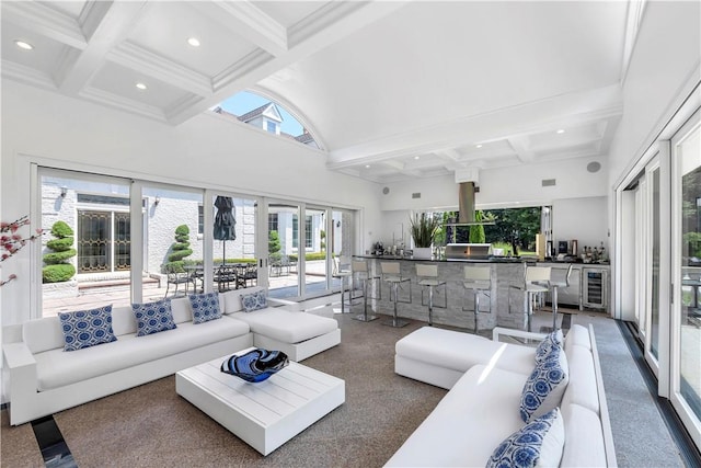 living room with beam ceiling, a healthy amount of sunlight, a high ceiling, and wine cooler