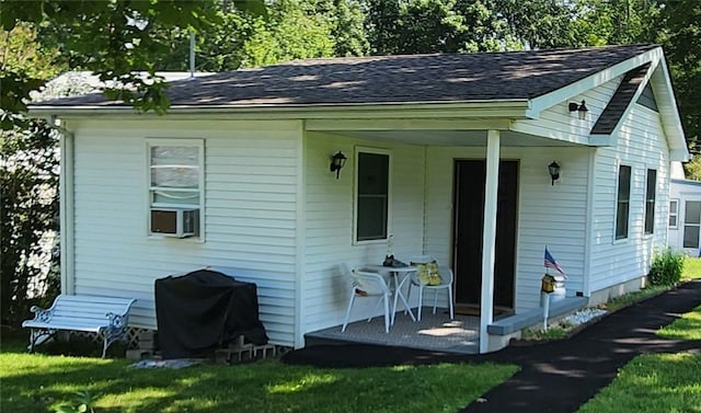 back of house with covered porch and a lawn