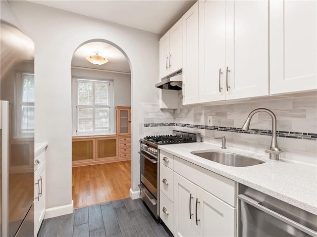 kitchen with light stone countertops, appliances with stainless steel finishes, dark hardwood / wood-style flooring, sink, and white cabinetry