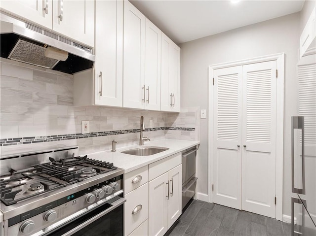 kitchen with light stone countertops, sink, tasteful backsplash, stainless steel gas range oven, and white cabinets