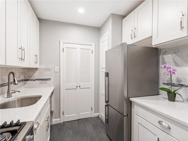 kitchen with sink, dark hardwood / wood-style floors, decorative backsplash, white cabinets, and appliances with stainless steel finishes