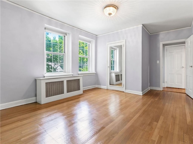 empty room featuring radiator heating unit, light hardwood / wood-style floors, and ornamental molding