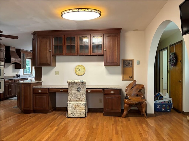 437 Lindholm Rd, Fallsburg, NY 12747 - kitchen with premium range hood, arched walkways, light countertops, light wood-type flooring, and glass insert cabinets