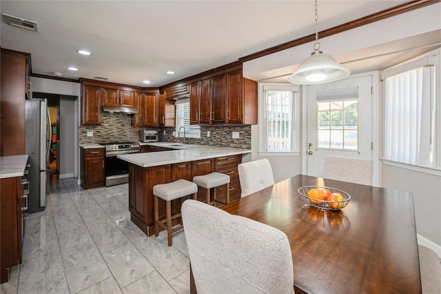 kitchen with a center island, hanging light fixtures, crown molding, sink, and appliances with stainless steel finishes