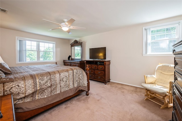 bedroom with ceiling fan, light colored carpet, and multiple windows