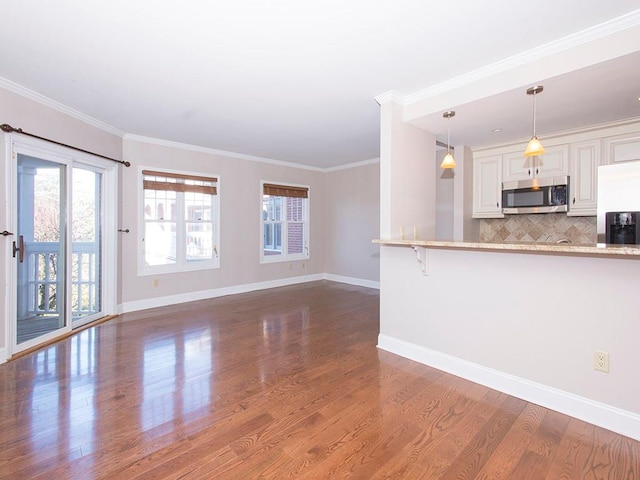 interior space featuring white cabinetry, stainless steel appliances, dark hardwood / wood-style flooring, crown molding, and a breakfast bar area