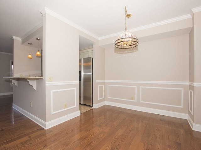 unfurnished dining area with dark wood-type flooring, a notable chandelier, and ornamental molding