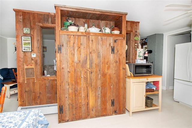 kitchen featuring white fridge, baseboard heating, wooden walls, and ceiling fan