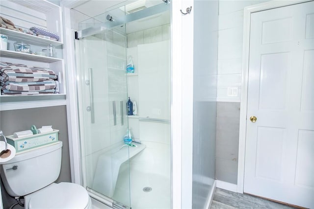 bathroom with toilet, an enclosed shower, and wood-type flooring