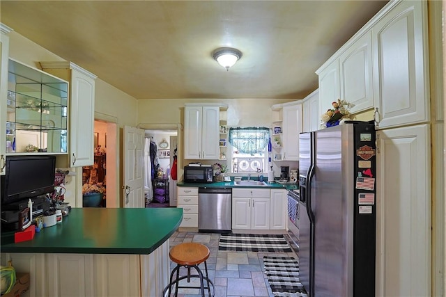 kitchen featuring white cabinetry, sink, kitchen peninsula, a breakfast bar, and appliances with stainless steel finishes