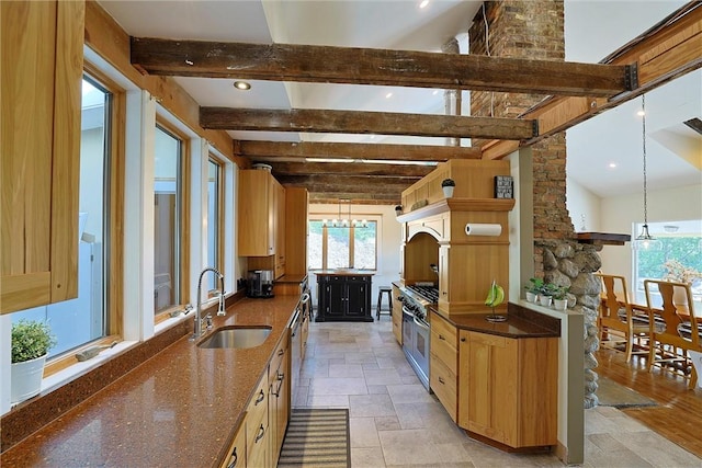 kitchen featuring high end range, sink, hanging light fixtures, dark stone countertops, and beam ceiling