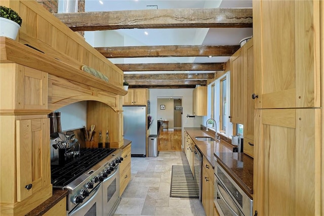 kitchen with light brown cabinetry, sink, beamed ceiling, and stainless steel appliances