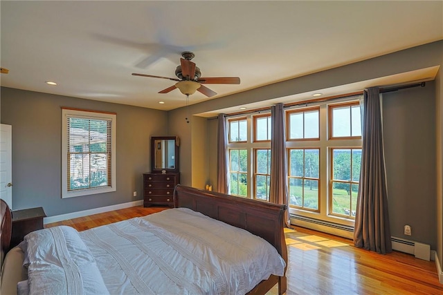 bedroom with light hardwood / wood-style floors, a baseboard radiator, and ceiling fan