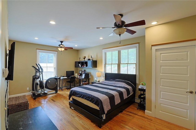 bedroom with ceiling fan, light hardwood / wood-style floors, and baseboard heating