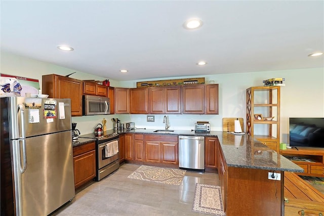 kitchen featuring dark stone counters, sink, light tile patterned floors, appliances with stainless steel finishes, and kitchen peninsula