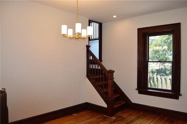 stairway with hardwood / wood-style floors, radiator, and a chandelier