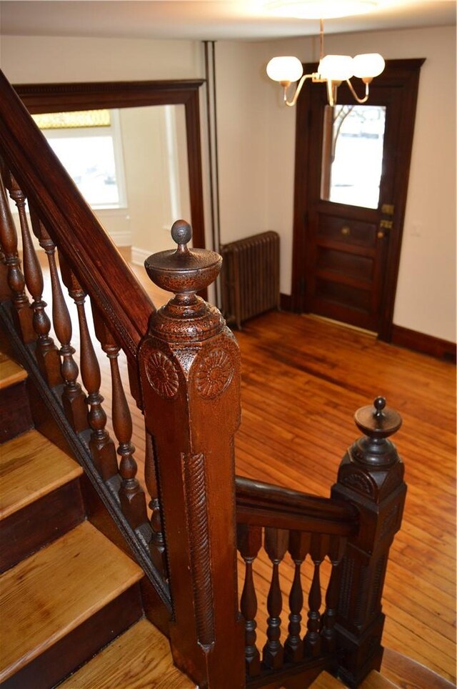 stairs with hardwood / wood-style flooring, a notable chandelier, and radiator