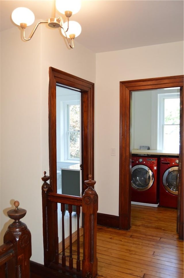 corridor featuring hardwood / wood-style floors, a chandelier, and washing machine and clothes dryer