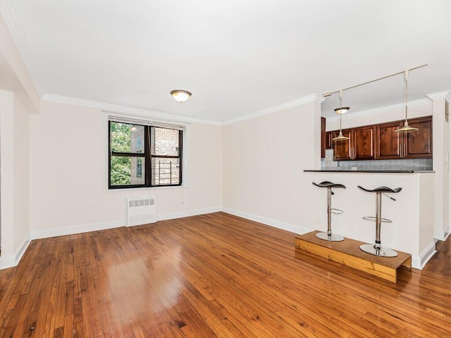 unfurnished living room featuring dark hardwood / wood-style flooring, ornamental molding, and radiator