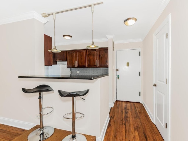 kitchen with dark wood-type flooring, white refrigerator, decorative backsplash, ornamental molding, and kitchen peninsula