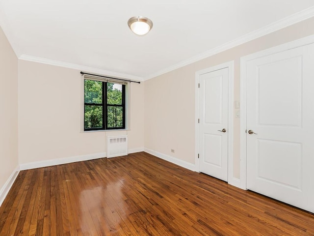 spare room with crown molding, dark hardwood / wood-style flooring, and radiator heating unit