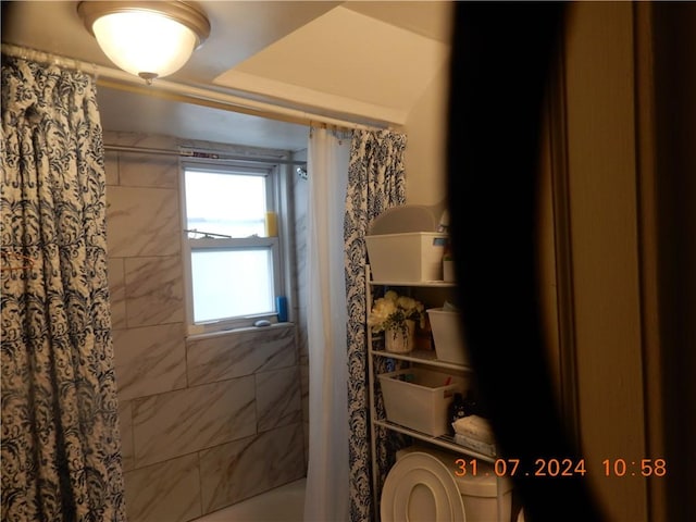 bathroom featuring a raised ceiling, toilet, and shower / tub combo with curtain