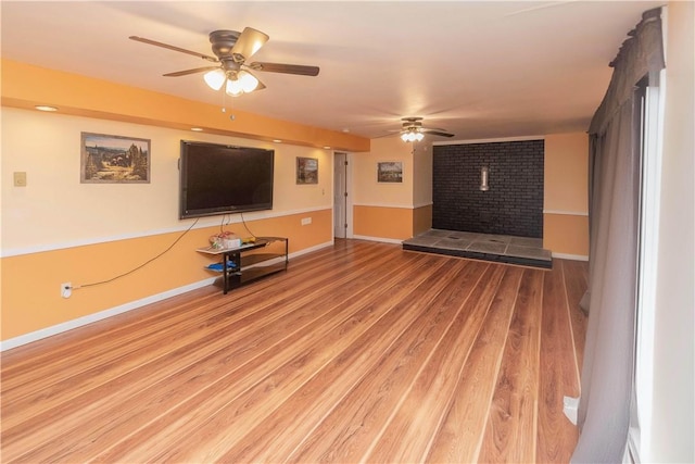 unfurnished living room with hardwood / wood-style floors, ceiling fan, and a tile fireplace