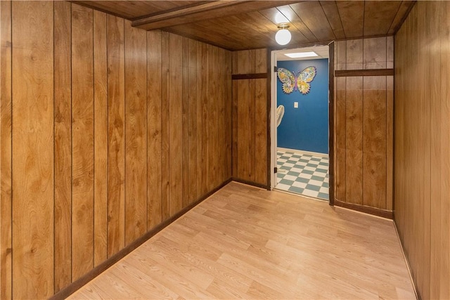 empty room featuring wooden ceiling, wooden walls, and light hardwood / wood-style flooring