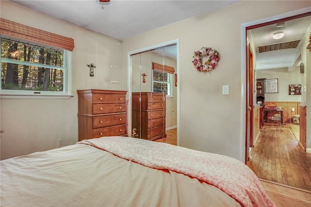 bedroom with ceiling fan, wood-type flooring, multiple windows, and a closet