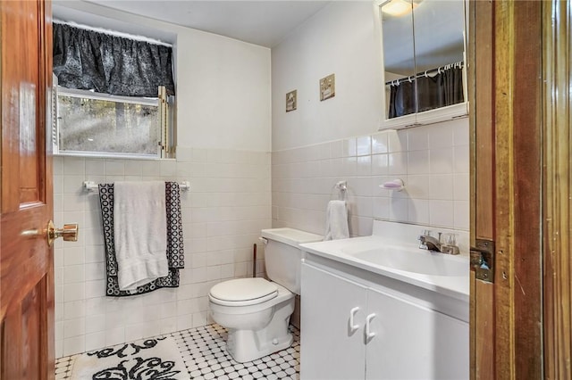 bathroom with tile patterned flooring, vanity, toilet, and tile walls