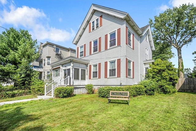 back of property featuring a sunroom and a lawn