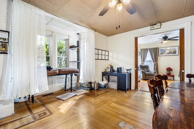 dining space with ceiling fan and a drop ceiling