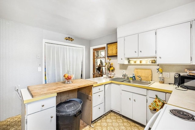 kitchen featuring white electric range oven, white cabinetry, and sink