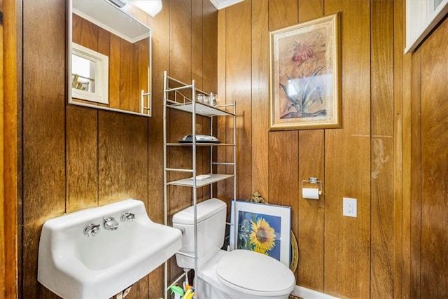 bathroom with wooden walls, sink, and toilet