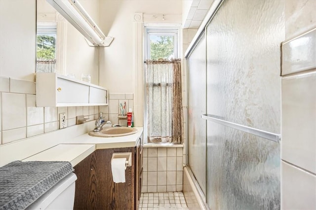 full bathroom with tile patterned floors, vanity, tile walls, enclosed tub / shower combo, and toilet