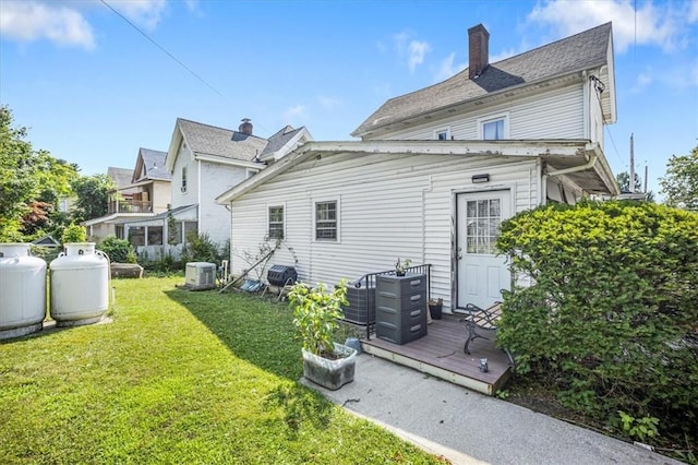 rear view of property featuring a lawn, central AC unit, and a deck