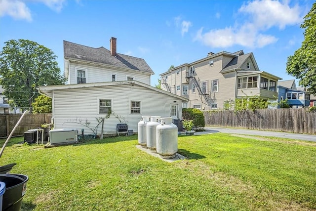 rear view of property with central AC and a yard