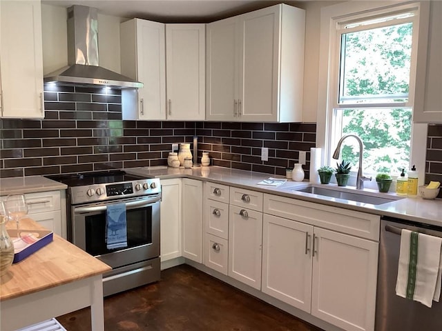 kitchen with sink, wall chimney exhaust hood, decorative backsplash, white cabinetry, and stainless steel appliances