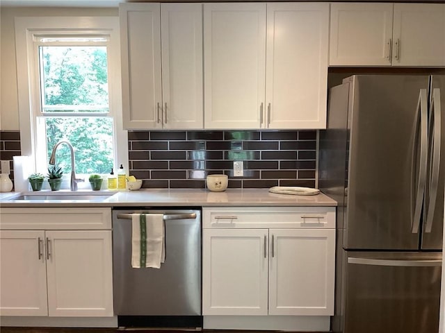 kitchen featuring decorative backsplash, white cabinetry, sink, and appliances with stainless steel finishes