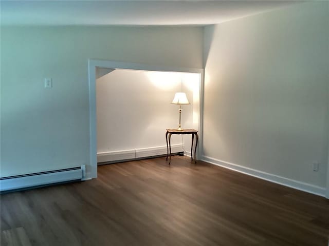 unfurnished room with dark wood-type flooring and a baseboard heating unit