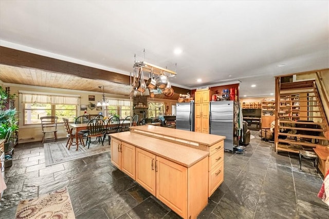 kitchen featuring light brown cabinetry, stainless steel refrigerator, a kitchen island, and wood ceiling